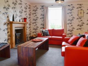 a living room with a red couch and a fireplace at Kennels Cottage - Beaufort Estate in Belladrum
