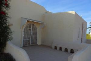 um edifício branco com um portão e um banco em Suite Vesta Villa Naïa Domaine Béluga Bounouma Kerkennah em Sfax