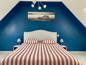 グロワにあるVilla Métisse Ile et Villas Groixの青いベッドルーム(ストライプシーツ付きのベッド付)