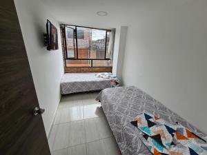2 camas en una habitación pequeña con ventana en Increíble Apartamento Familiar, en Bogotá