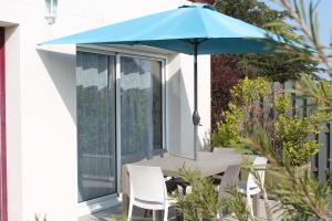 a table with a blue umbrella on a balcony at Villa Garance Ile et Villas Groix in Groix