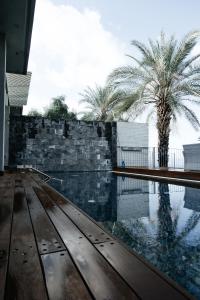 a swimming pool with a stone wall and palm trees at BigPool - Diamond Mansion in Had Nes