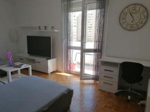 a living room with a television and a clock on the wall at Apartman Petra in Pula +3 photos