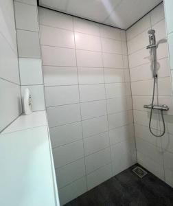 uma casa de banho em azulejos brancos com um chuveiro. em Appartement City Enschede (free private parking) em Enschede