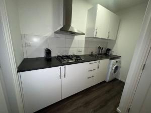 uma cozinha com armários brancos, um lavatório e um fogão em Appartement City Enschede (free private parking) em Enschede