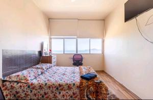 a bedroom with a bed and a desk and a window at STUDIO G VISTA ESPETACULAR in Santos
