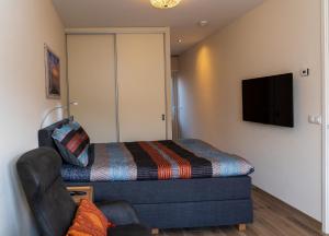 a bedroom with a bed and a couch and a tv at De Sprink - Luxe Kamer - Strand & Zee in Zoutelande