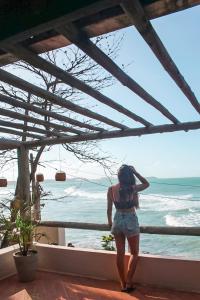 Una mujer parada en un balcón con vistas al océano en Abacate Casa do Mar en Pipa