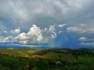 a rainbow in the sky over a green mountain at Chalés Santa Luzia in Santo Antônio do Pinhal