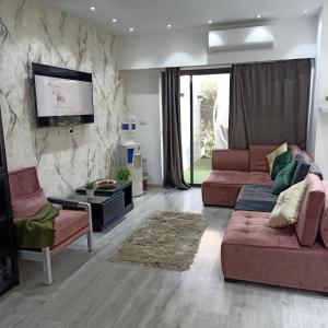 ein Wohnzimmer mit zwei Sofas und einem Flachbildfernseher in der Unterkunft 2 Bedroom+Garden, Lakes near AUC in New cairo + 10 Fotos