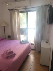a bedroom with a bed with pink sheets and a window at TODO AL ALCANCE DE LA MANO in Mendoza
