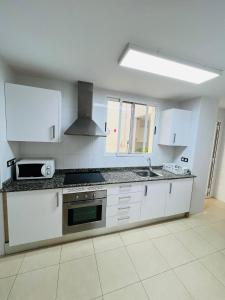 佩尼斯科拉APARTAMENTO SITUADO EN EL CENTRO CON 3 HABITACIONES, DISPONE DE AIRE ACONDICIONADO Y WIFI A 150m DE LA PLAYA Y EL CASTILLO的厨房配有白色橱柜和炉灶烤箱 更多28张照片