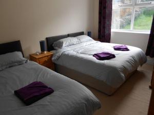 2 Betten in einem Schlafzimmer mit lila Handtüchern darauf in der Unterkunft Hillsborough View in Ilfracombe