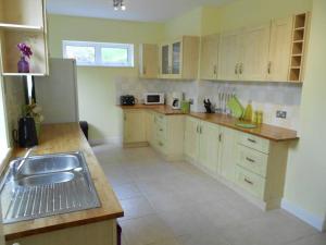 eine große Küche mit Holzschränken und einem Waschbecken in der Unterkunft Hillsborough View in Ilfracombe