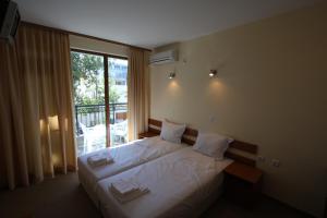 a bedroom with a bed and a large window at Family hotel Deykin in Sunny Beach +65 photos