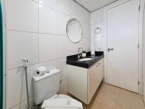 La salle de bains blanche est pourvue d'un lavabo et d'un miroir. dans l'établissement Portal Meireles Vista Mar 2 Suítes 150m Beira Mar, à Fortaleza