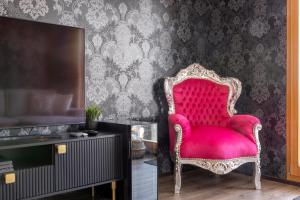 Cette chambre comprend une chaise rouge et une télévision. dans l'établissement Once Upon A Time, à Loèche-les-Bains