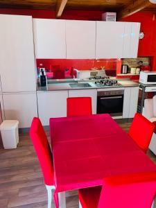 a kitchen with a red table and red chairs at Anzio a picco sul mare! in Anzio
