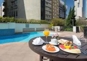 uma mesa com comida e um copo de suco de laranja em Kaza Noah The Universe Paulista Bela Vista em São Paulo