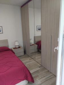 a bedroom with a pink bed and a mirror at La Dependance in Centro in Follonica