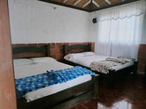 two beds sitting in a room withermottermottermott at Hotel campestre manantial del Quindio in Montenegro