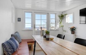 uma sala de jantar com uma mesa de madeira e algumas janelas em Heidis Residence-Sandkaas, Bornholm em Allinge