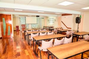 una clase con mesas, sillas y una pantalla en Samkauta Hotel & Suite, en Juliaca