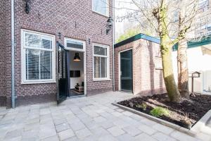 a brick building with a tree in front of it at Plantage Garden Apartments in Amsterdam