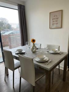 a dining room table with chairs and a vase with flowers on it at Modern East London Apartment in London