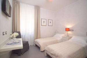 サン・ジェーミニにあるStazione di Posta San Geminiのベッドルーム1室(ベッド2台、テーブル、窓付)