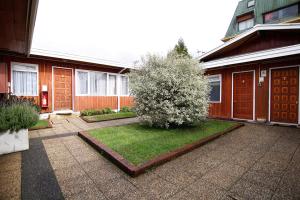 una casa con un patio con un árbol delante en Hotel y Cabañas Villarrica, en Villarrica