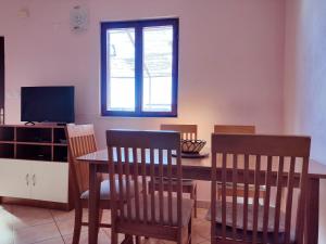 uma sala de jantar com uma mesa e cadeiras e uma televisão em Studio Apartment em Rogoznica