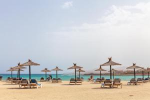 a group of chairs and umbrellas on a beach at Villa Rubi 19 Golf Private Pool Caleta de Fuste By Holidays Home in Caleta De Fuste