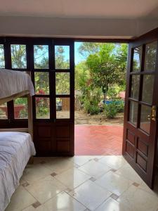 a bedroom with a bed and a view of a yard at Casa Hotel Arcadia Minca in Minca