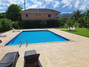 a swimming pool with two chairs and a house at palmview estate townhouse in Mammee Bay