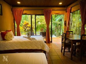 a bedroom with two beds and a dining room with a table at Hotel Heliconias Nature Inn & Hot Springs in Fortuna