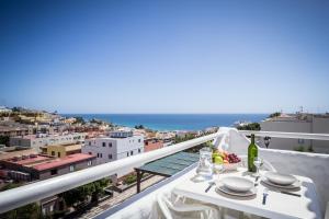 a table on a balcony with a view of the city at Apartamentos NataLis in Morro del Jable