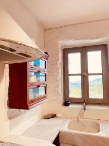 een badkamer met een wastafel en een raam bij Authentic Kea island house in Otziás