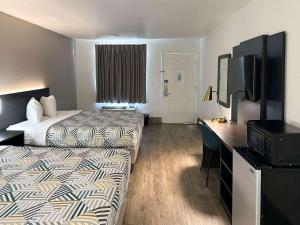 um quarto de hotel com duas camas e uma televisão de ecrã plano em Motel 6-Pooler, GA - Savannah Airport em Savannah