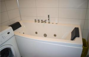 a bath tub in a bathroom next to a washing machine at Lovely Home In Krager With Wifi in Kragerø