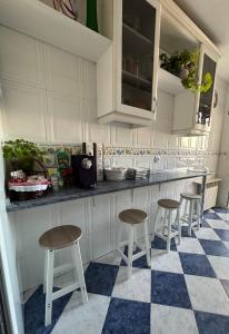 Madera de Olmo في مدريد: مطبخ مع خزائن بيضاء وكراسي البار