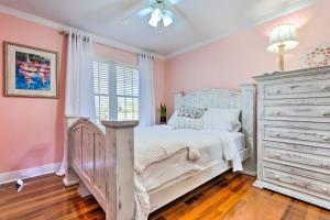 a bedroom with a white bed and a dresser at Ocean Springs Home with Fire Pit and Game Room! in Biloxi