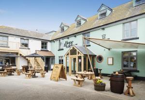 eine Terrasse mit Tischen und Bänken vor einem Gebäude in der Unterkunft Hope & Anchor in Hope-Cove
