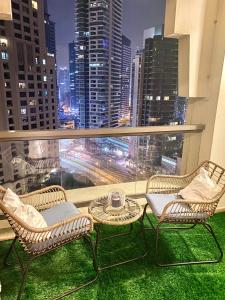 Duas cadeiras e uma mesa numa varanda com vista para o horizonte da cidade. em Charming spacious studio apartment in the heart of JBR By SWEET HOMES no Dubai