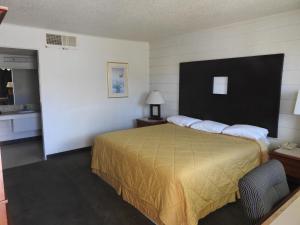 Habitación de hotel con cama con colcha amarilla en Economy Inn, en Socorro