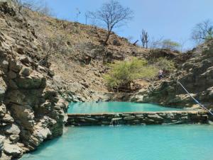 a pool of blue water in a rocky canyon at Aylluwasihostel in Máncora
