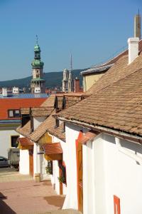 a row of white buildings with a lighthouse in the background at Vinosseum Bor- és Apartmanház in Sopron