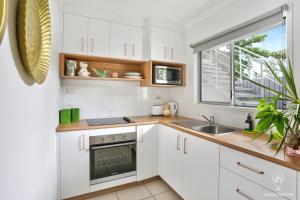 a kitchen with white cabinets and a sink and a window at Tropicana Pineapple in Cairns North