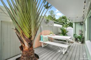 a porch with a bench and a palm tree at Tropicana Pineapple in Cairns North