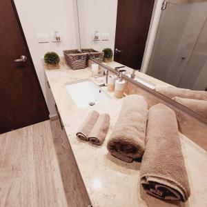 a bathroom with a sink and a mirror and towels at Syrena Luxury Caribbean in Playa del Carmen